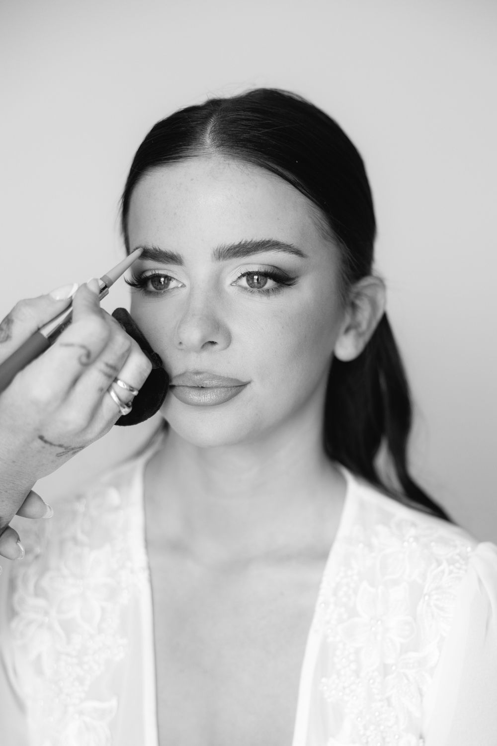 Black and white photo series showing makeup application process with dramatic eye makeup and glossy lips.