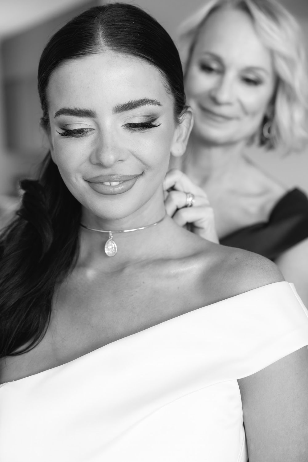 An intimate black and white portrait showing a touching moment during wedding preparations.