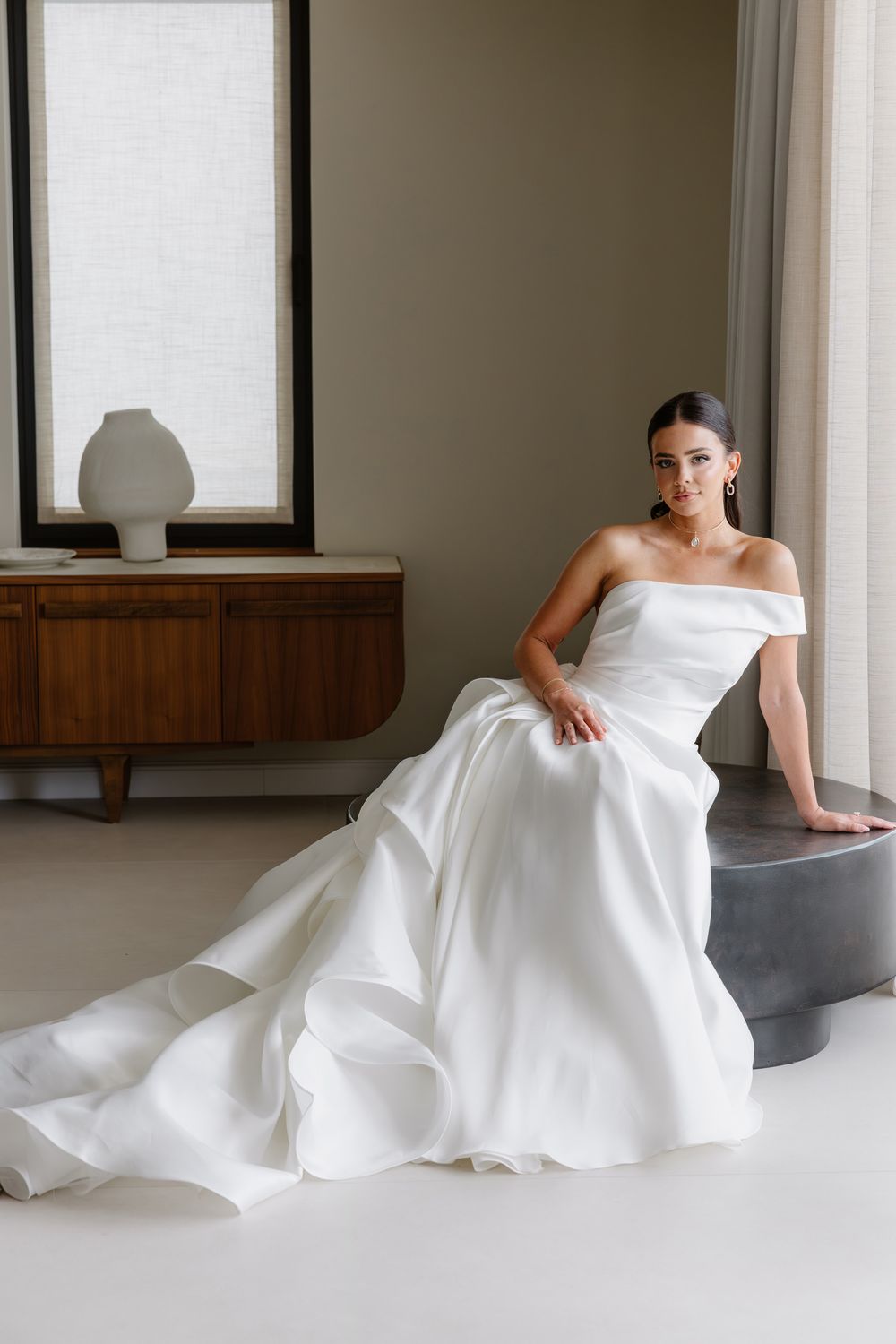 A flowing white wedding gown is elegantly draped across a minimalist interior setting in a series of artistic poses.
