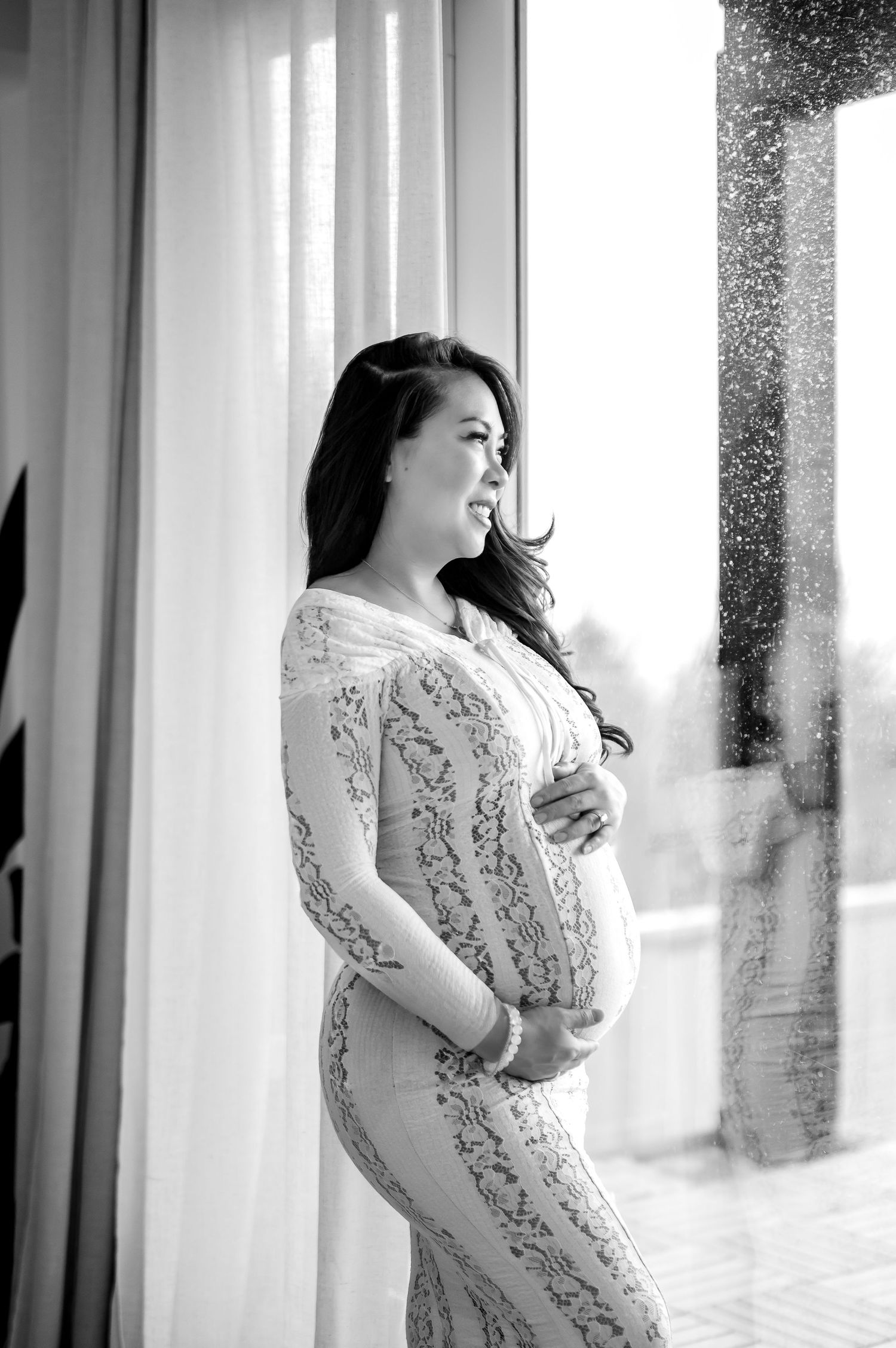 Black and white portrait series of a woman in lace dress posing elegantly against sheer curtains in natural light.