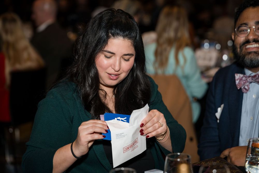 Attendees reading materials at tables during a formal event.