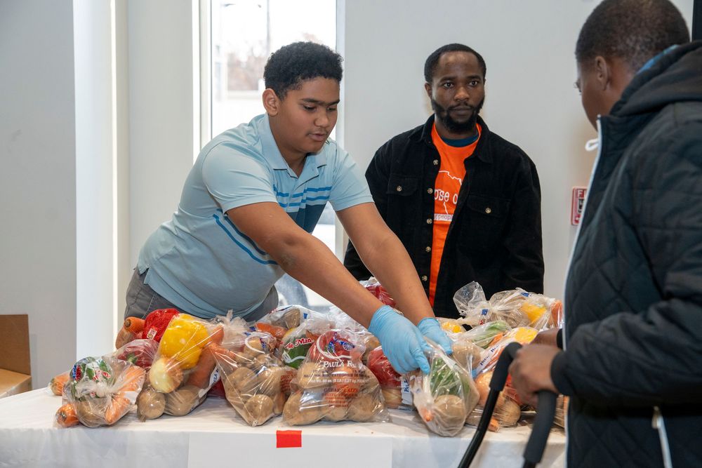 People sitting at tables preparing gift bags and packages for an event.