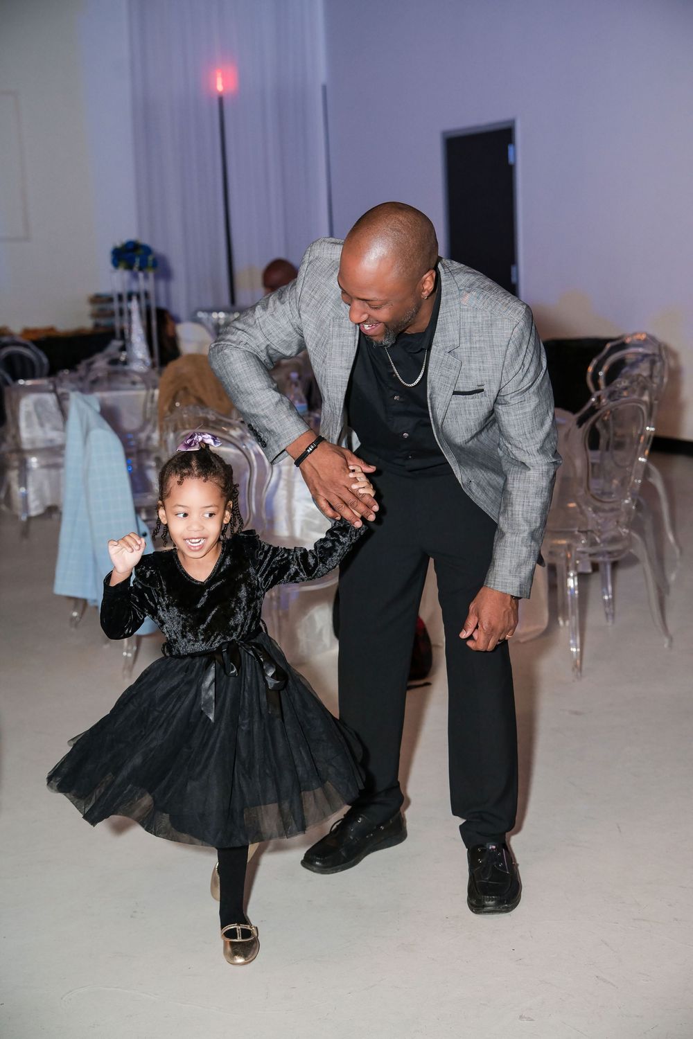 A heartwarming father-daughter dance moment at a formal event with matching black attire.