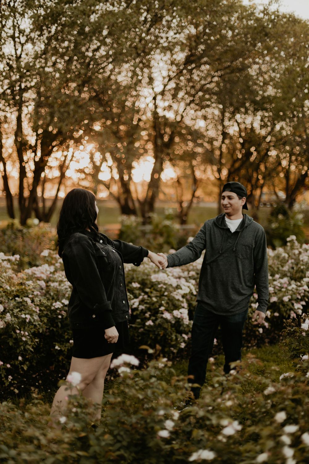 Casual couple walking through a garden during golden hour.