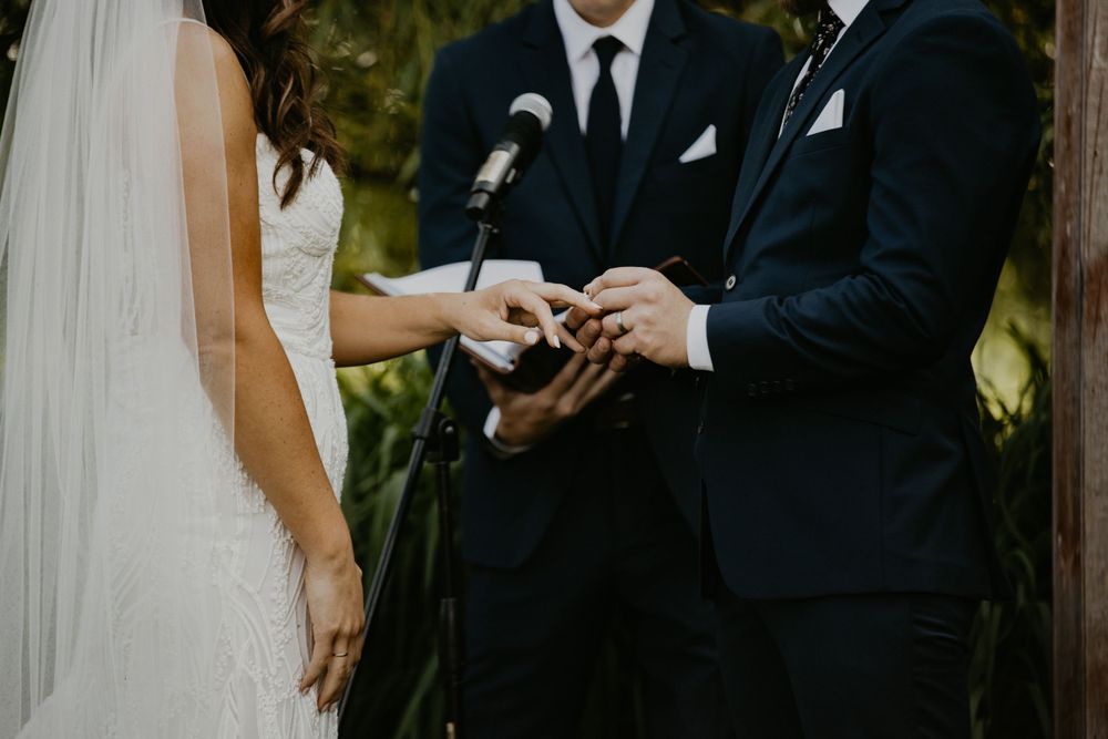 A couple shares an intimate moment during their wedding ceremony outdoors.