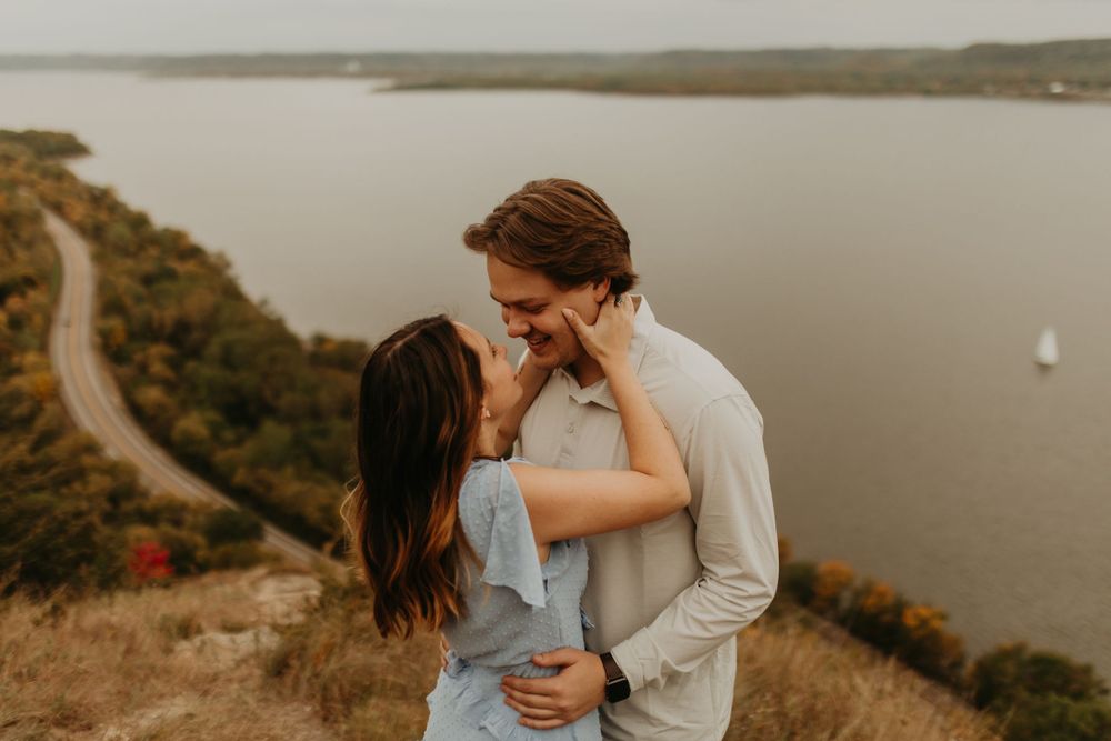Couple sharing an intimate moment on a coastal cliff during golden hour.