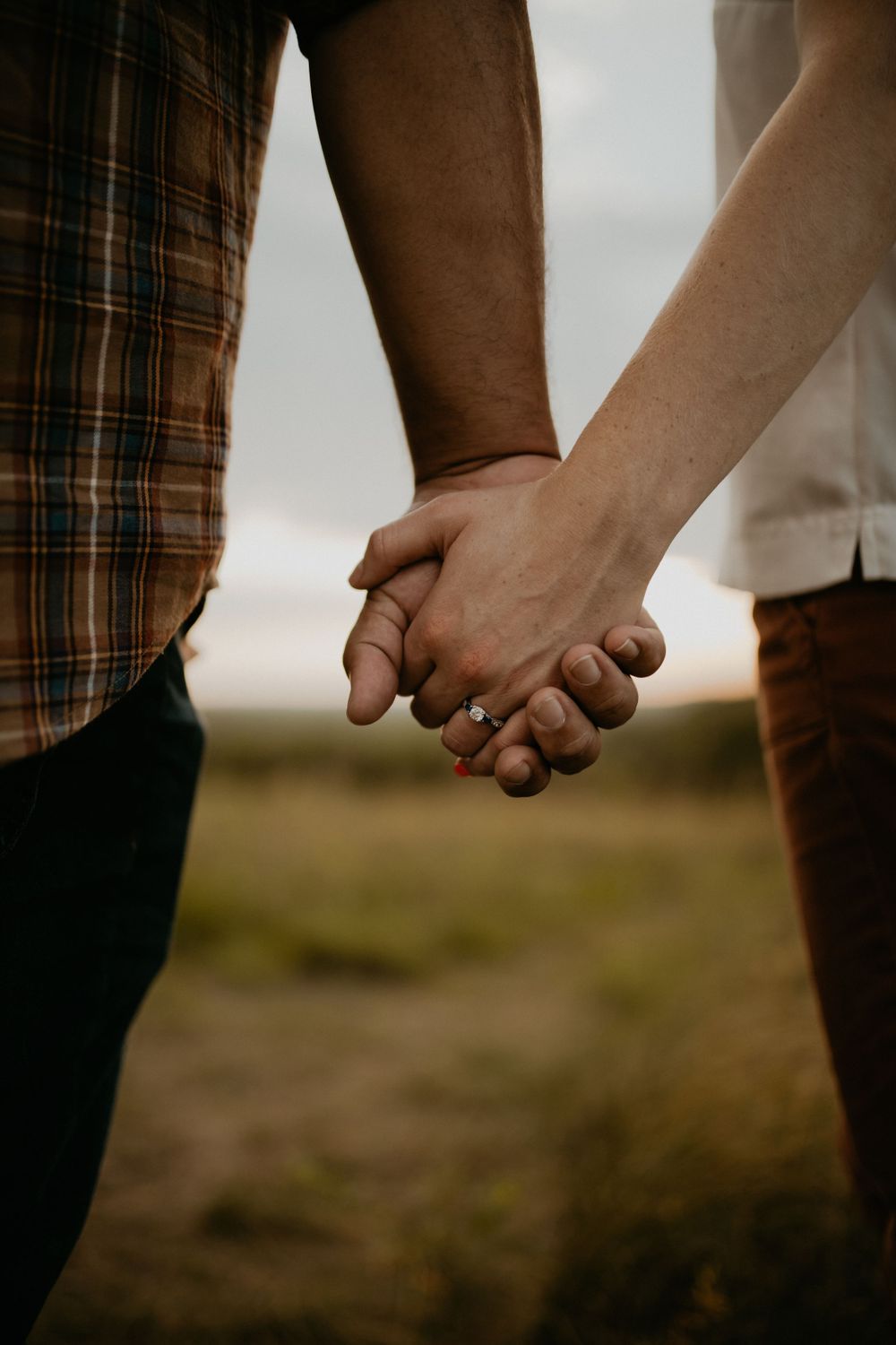 Close-up shots of hands holding each other against a natural outdoor background.