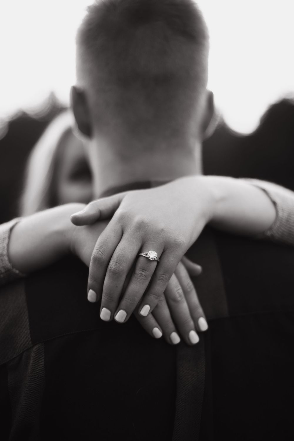 Close up black and white photo of hands embracing showing engagement ring.