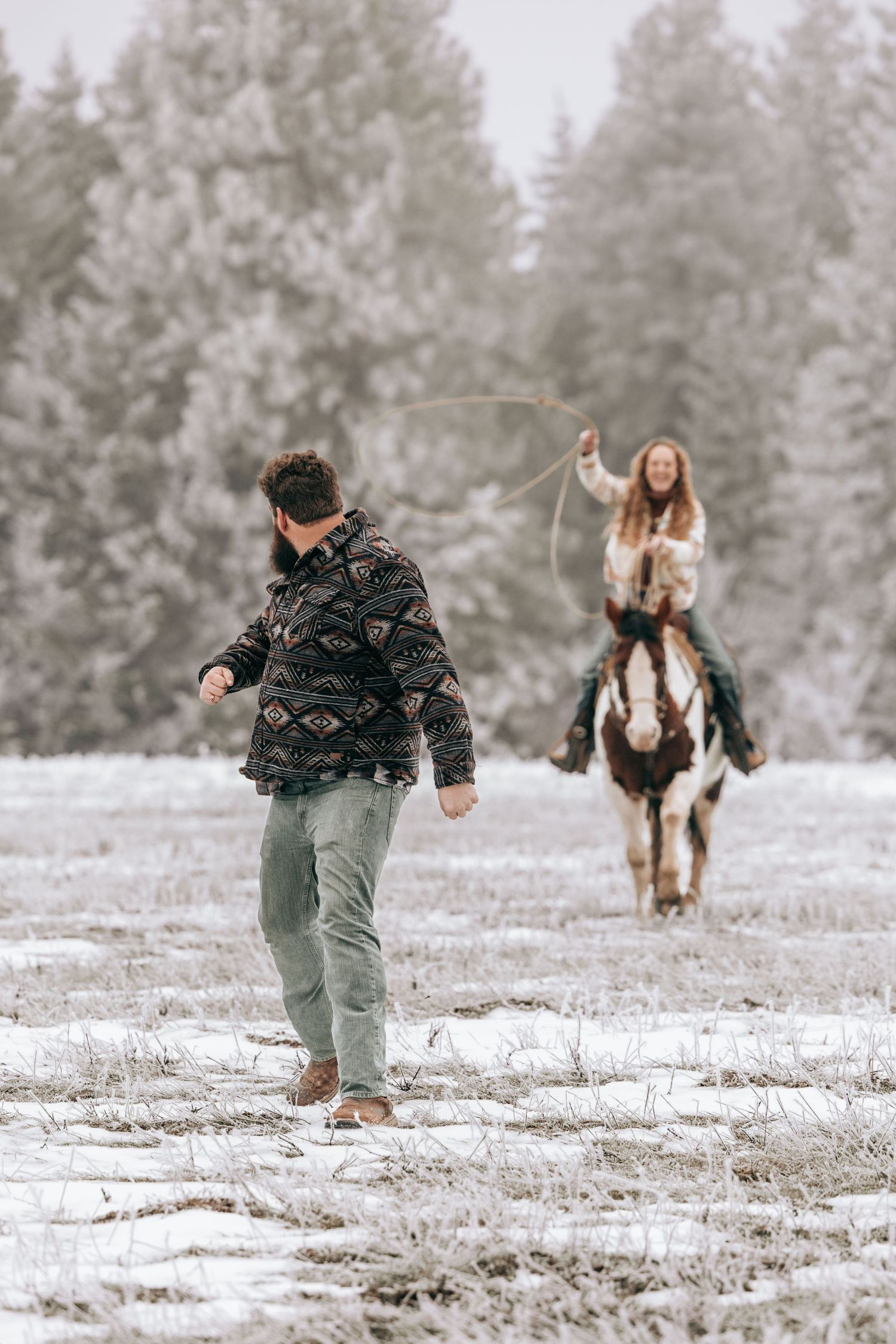 Cle Elum, WA engagement photography. Woman sitting on horse swinging a rope running toward running man.