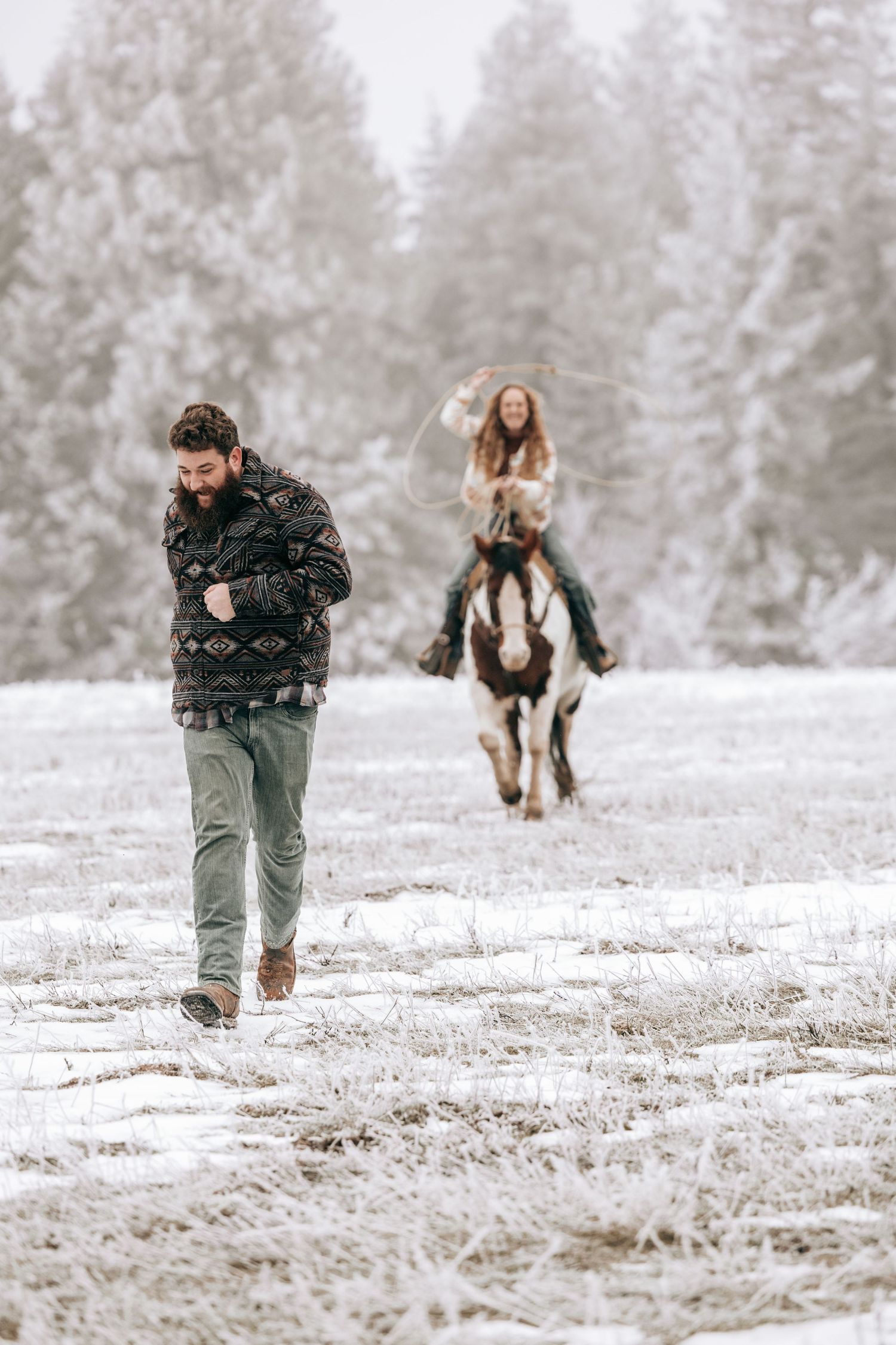 Cle Elum, WA engagement photography. Woman sitting on horse swinging a rope running toward running man.