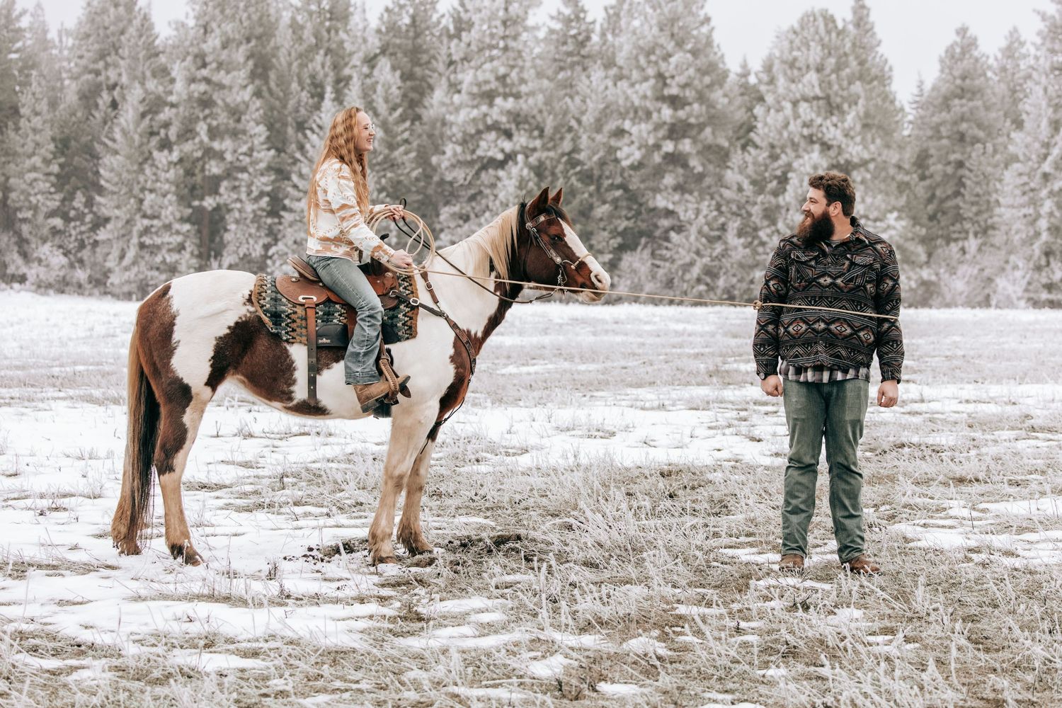 Cle Elum, WA engagement photography. Woman sitting on horse laughing with a man roped in front of horse.