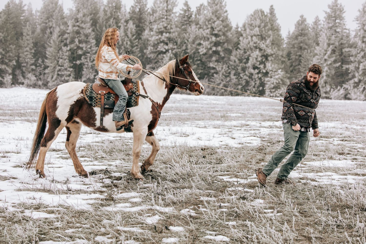 Cle Elum, WA engagement photography. Woman sitting on horse roping tall man. A rope is wrapped around them.