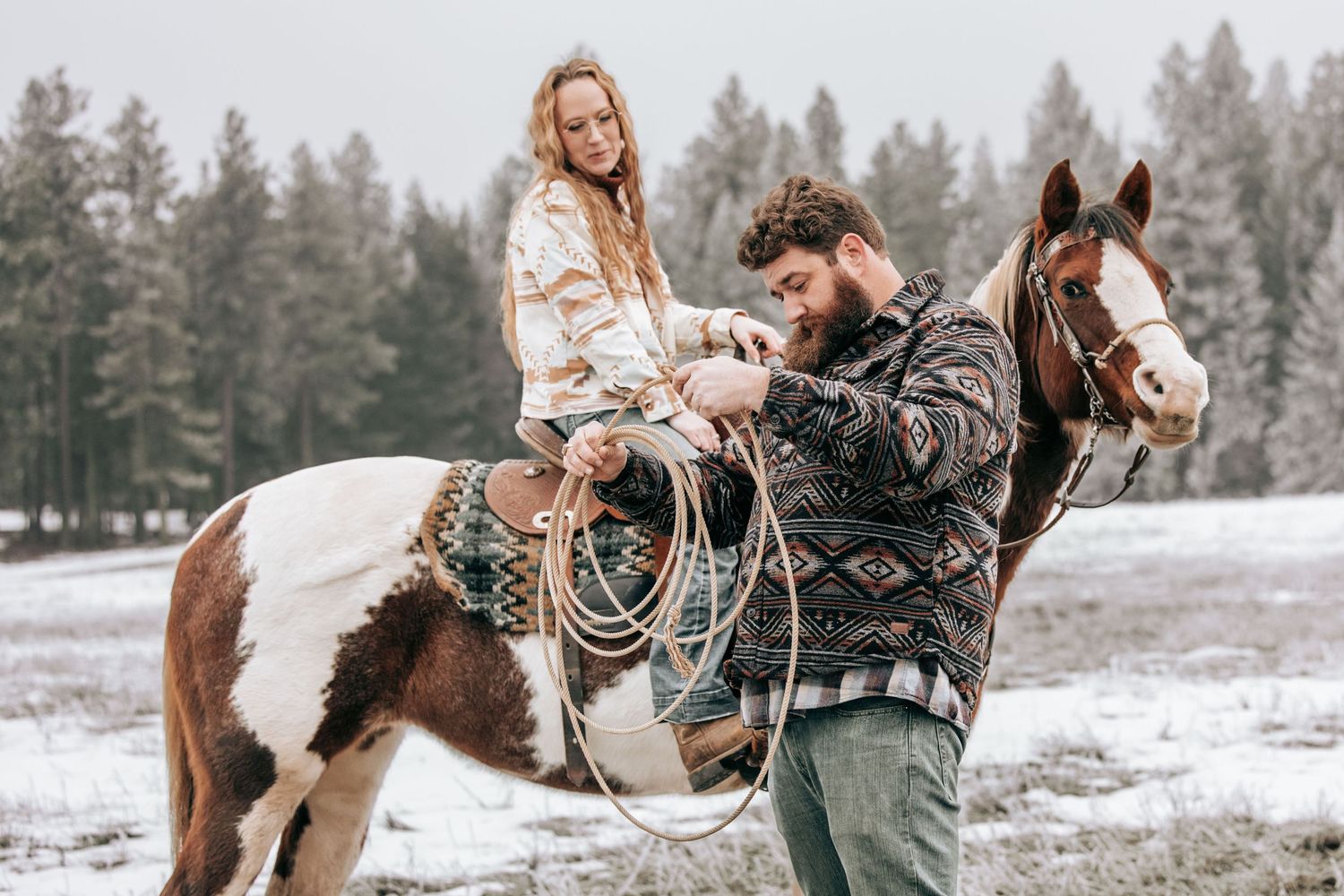 Cle Elum, WA engagement photography. Woman sitting on horse kissing tall man. A rope is wrapped around them.