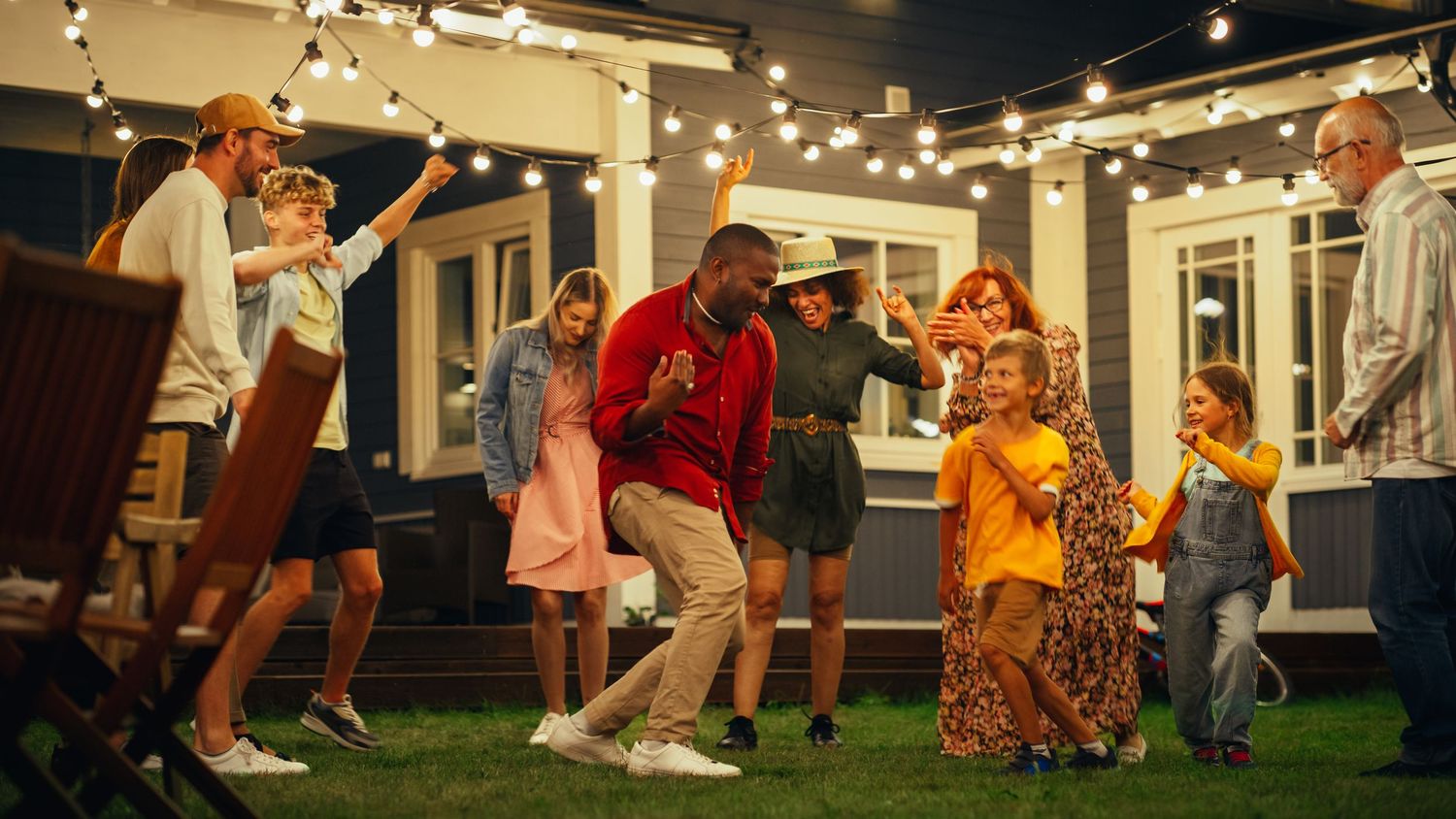 People dancing and celebrating together on a backyard patio with string lights creating a festive atmosphere.