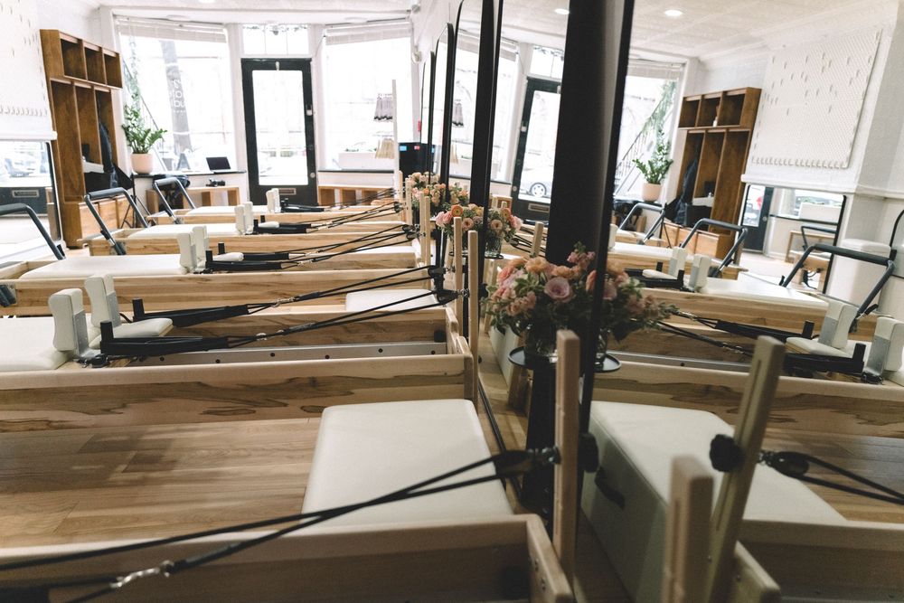 Woodworking workshop interior with raw lumber storage racks, workbenches and natural lighting through large windows.