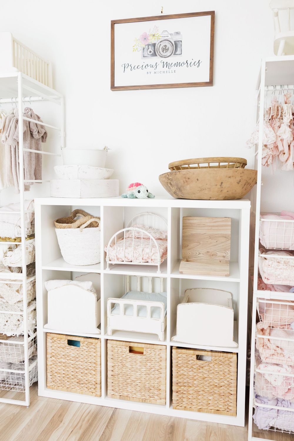 White cubby shelf with wicker baskets and miniature furniture in a bright, organized photography studio.