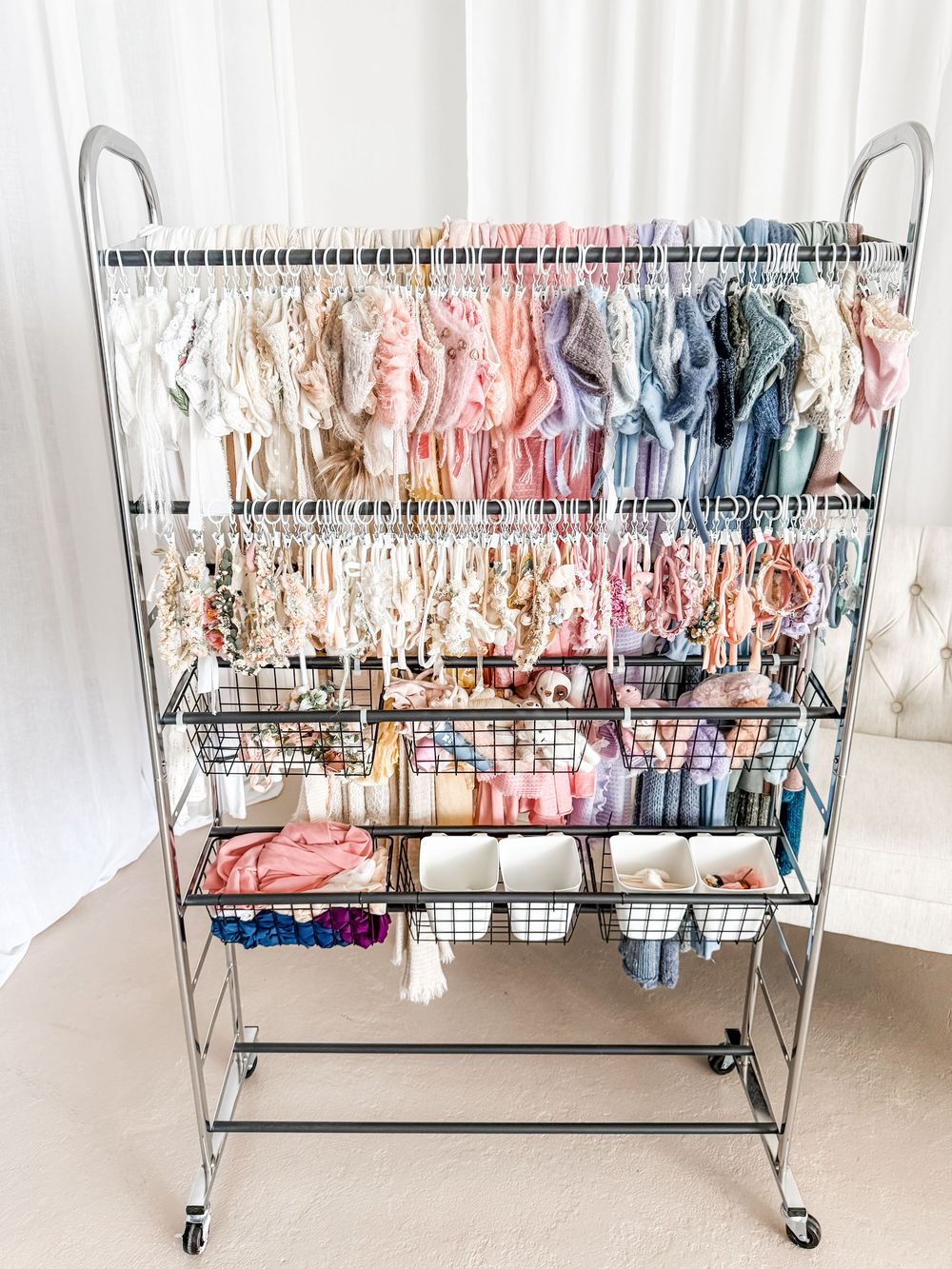 A clothing rack display showing baby clothes and accessories organized neatly on multiple shelves and hangers.