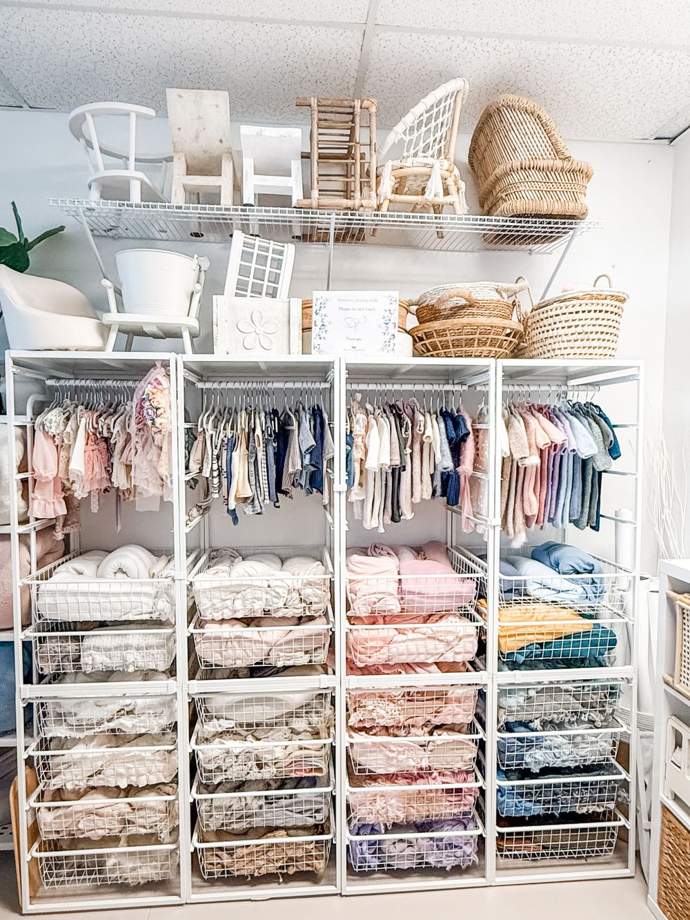 Organized linen closet with wire shelving displaying neatly folded bedding and textiles in soft neutral and pink tones.