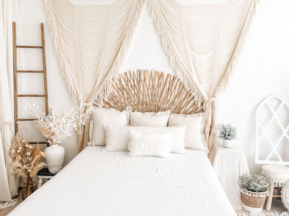 A collage of neutral boho bedroom decor with macrame wall hangings, white bedding, and natural woven accents.