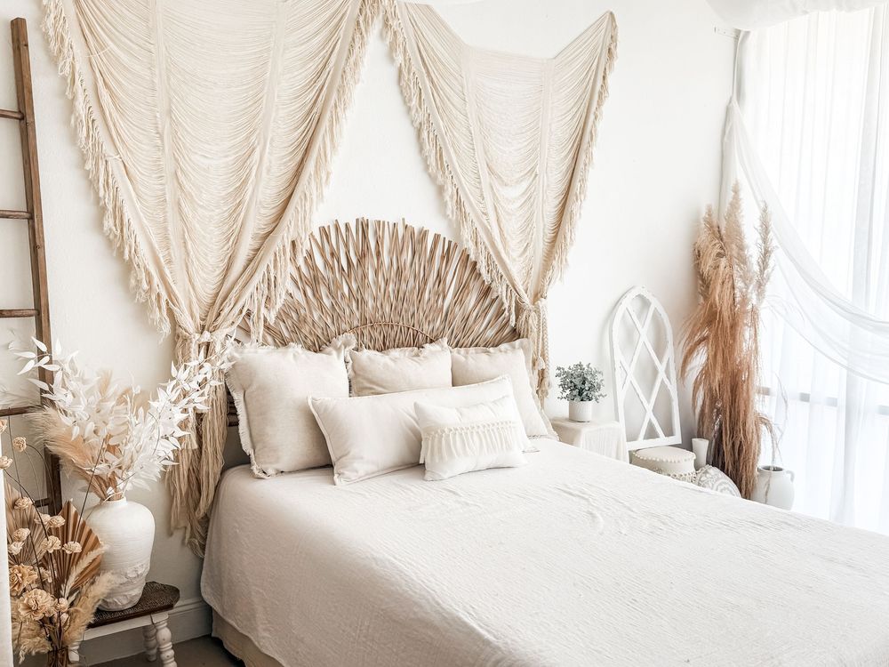 Boho-style bedroom interior with neutral colors, pampas grass decor, and white bedding in soft natural light.