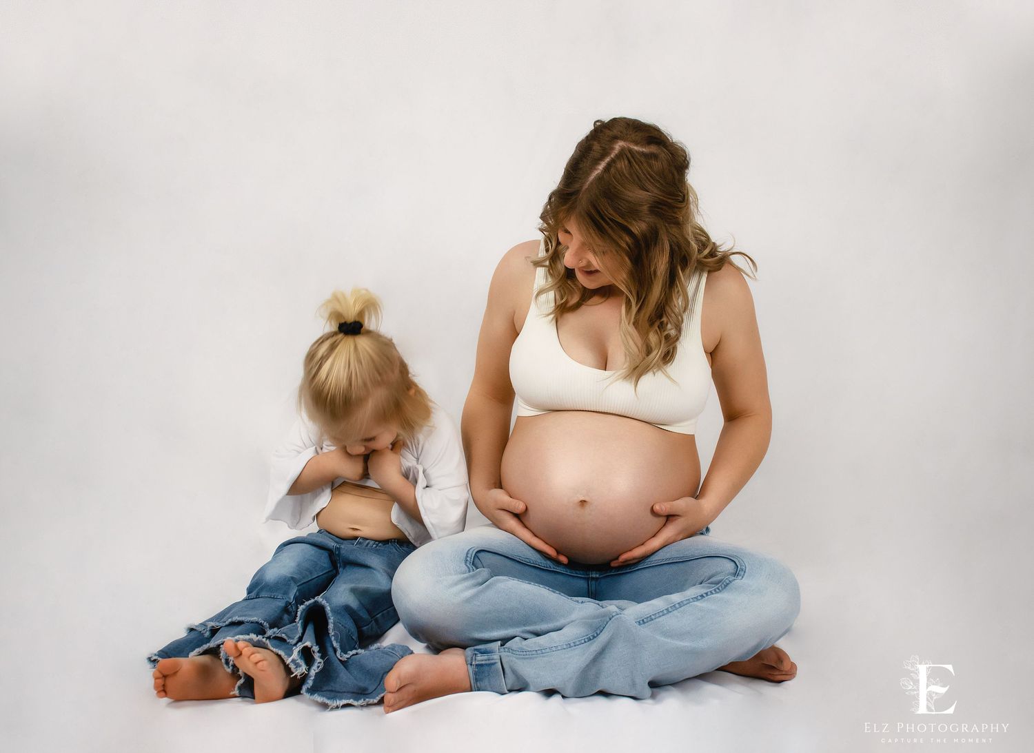 Maternity photo series showing pregnancy progression with child on white background in Williston, North Dakota.