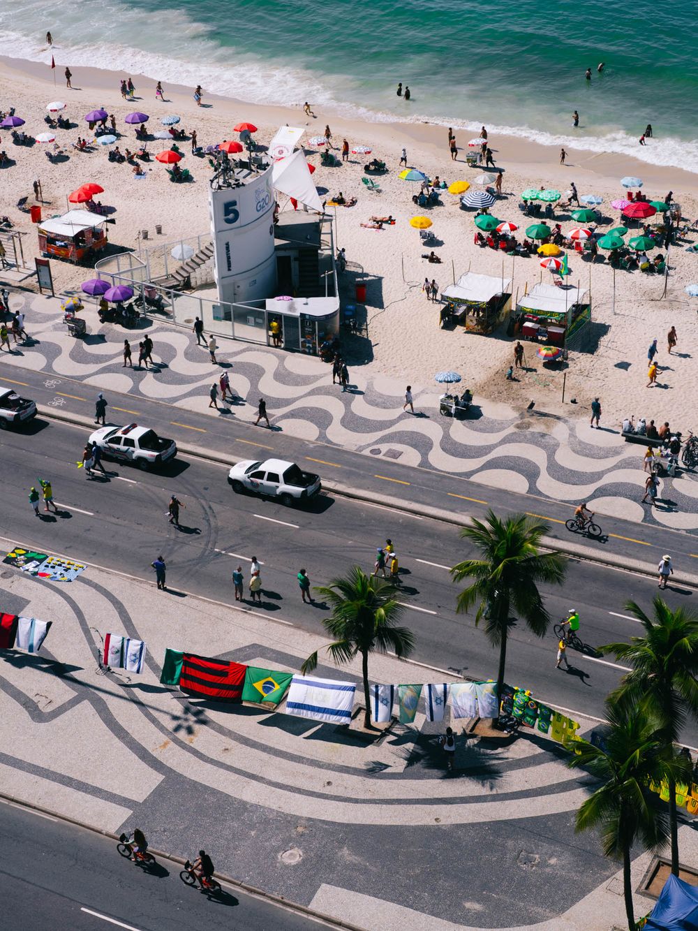 Aerial view of Copacabana Beach in Rio de Janeiro showing the iconic wavy mosaic sidewalk pattern and beachgoers.