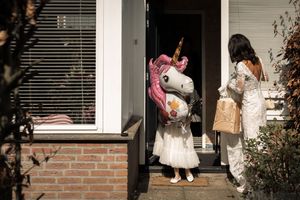 Trick-or-treaters in Halloween costumes walk up to a house's front door at night to collect candy.