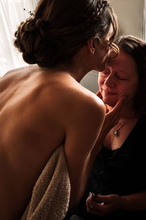 Two people share an intimate moment in soft window light, creating a romantic silhouette.