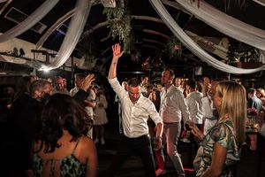 Wedding guests dance and celebrate together on a dimly lit dance floor at an evening reception.