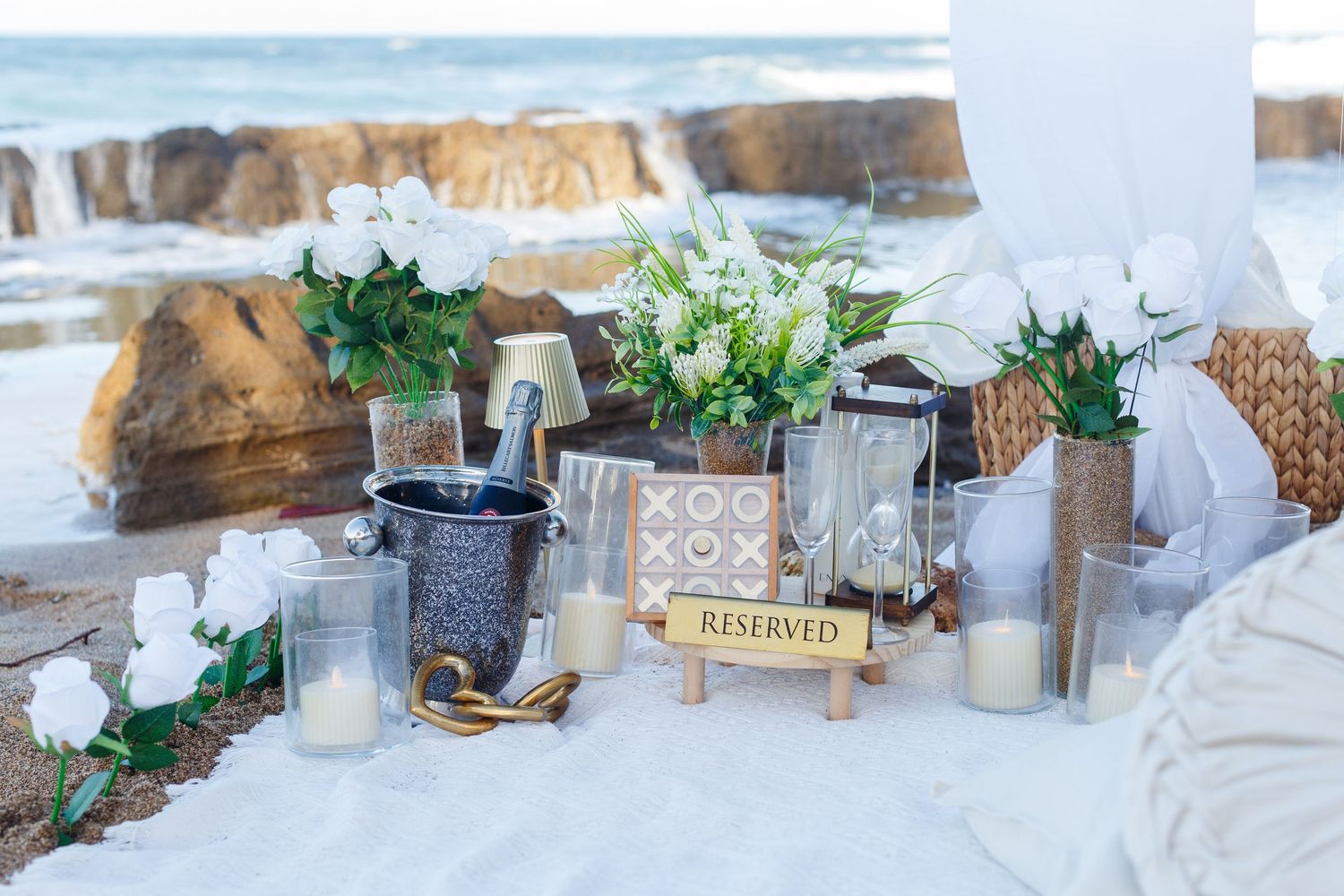 Proposal and engagement session. Decorative setup on the beach including white roses and champagne. Kikita Surf Beach, Dorado, Puerto Rico.