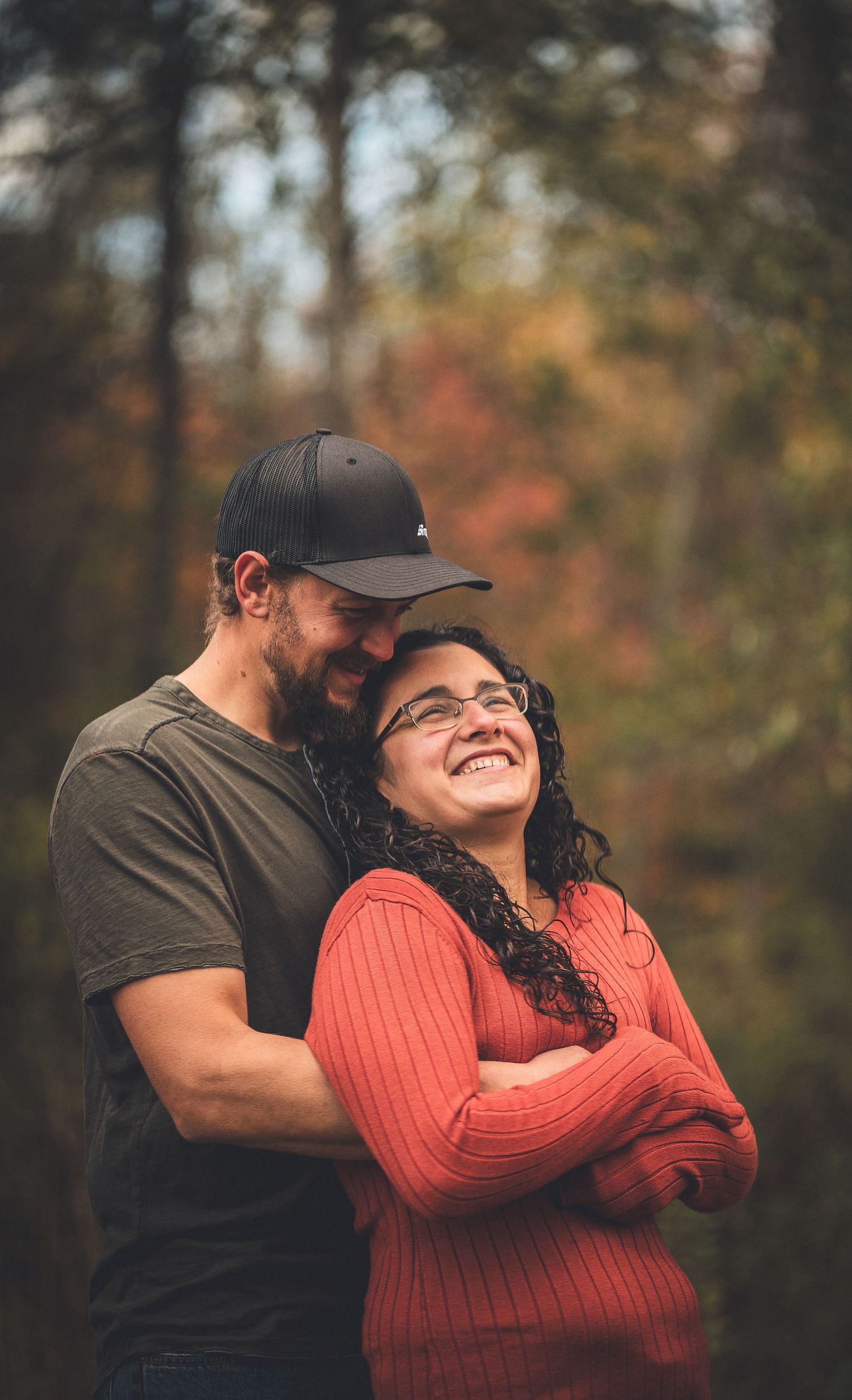 Candid autumn portrait of couple laughing together in forest setting.