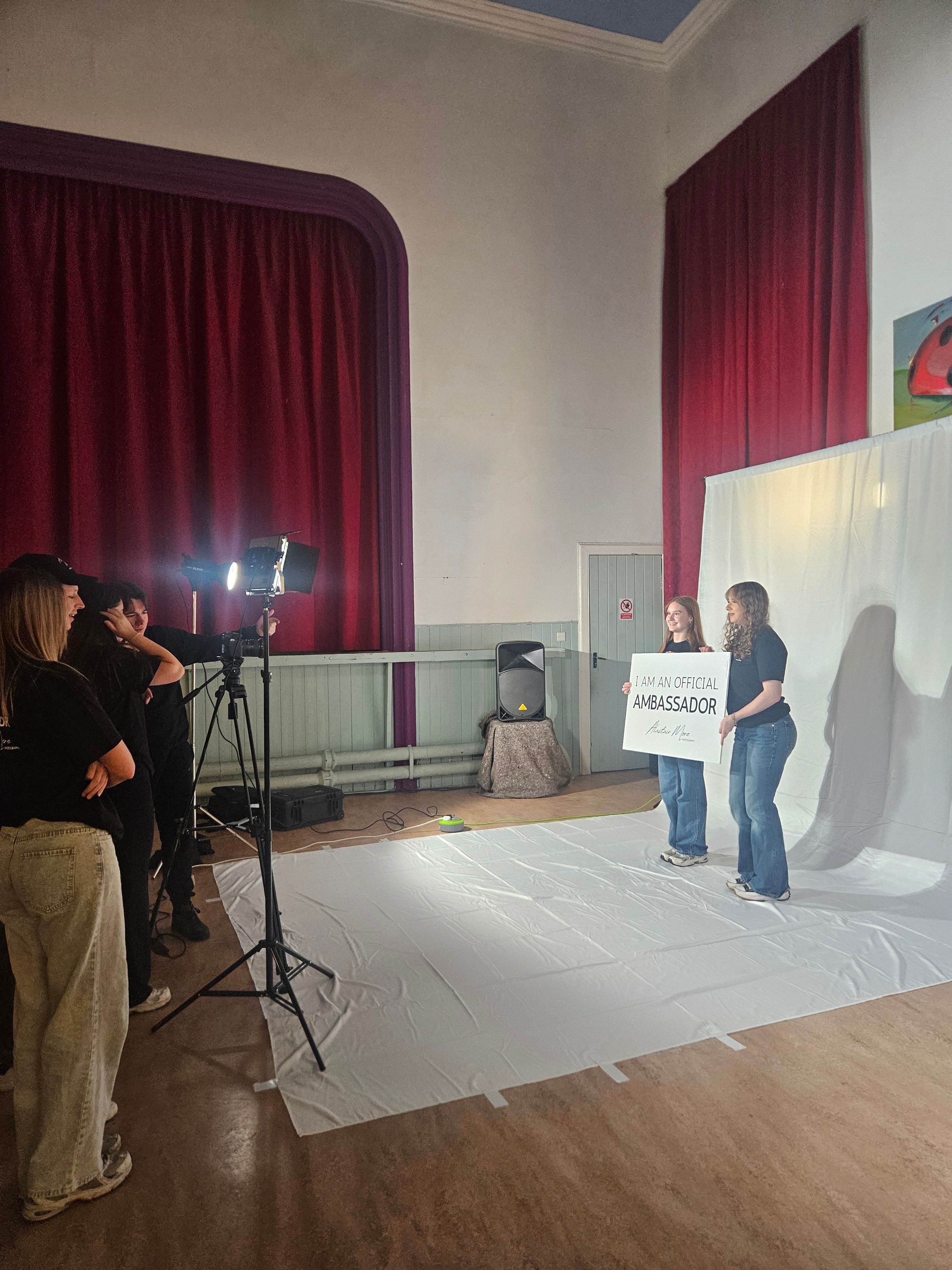 A photo studio setup showing multiple shots of lighting equipment and red curtains against white walls during a photoshoot.