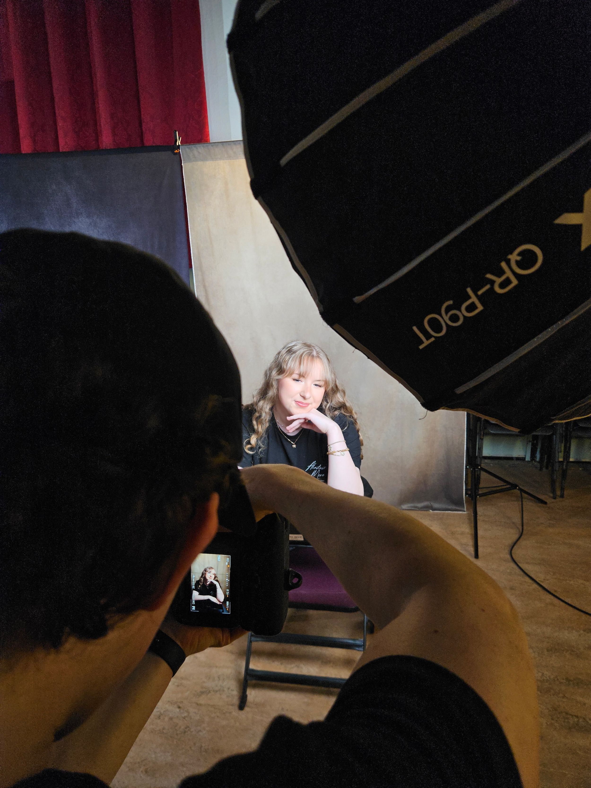 Behind-the-scenes photo of a professional photoshoot setup with lighting equipment and softboxes in a studio setting.