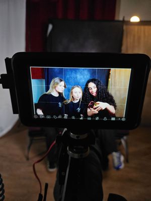 Behind the scenes view of video production monitors showing multiple camera angles in a dark studio setting.
