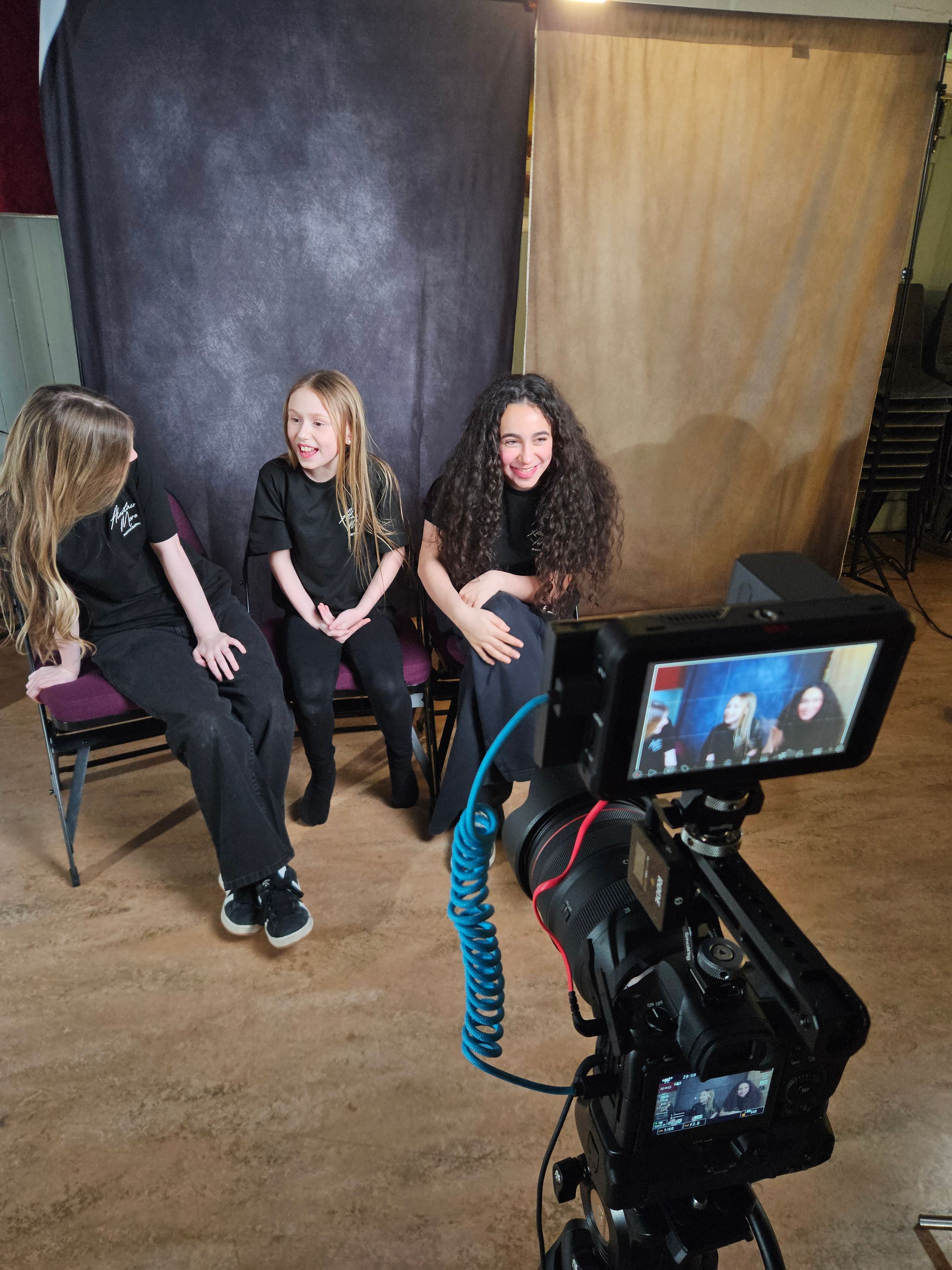 Behind the scenes view of a camera setup showing people crouching to get the perfect low angle shot in a studio.