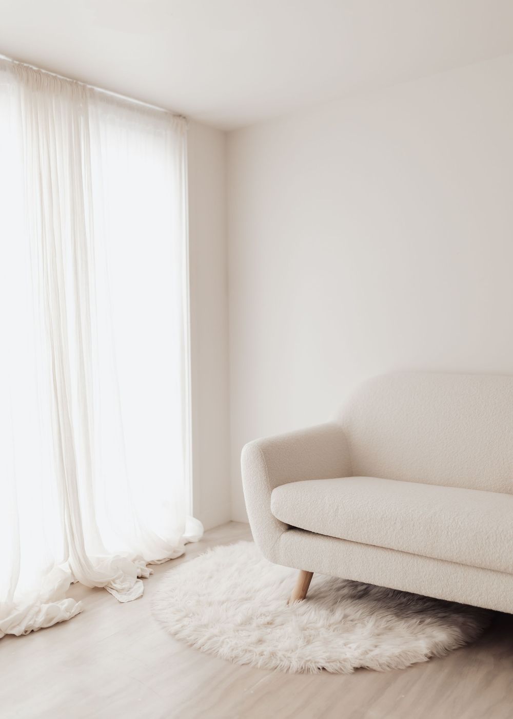 A minimalist white bedroom interior with flowy curtains and plush bedding creating a serene atmosphere.