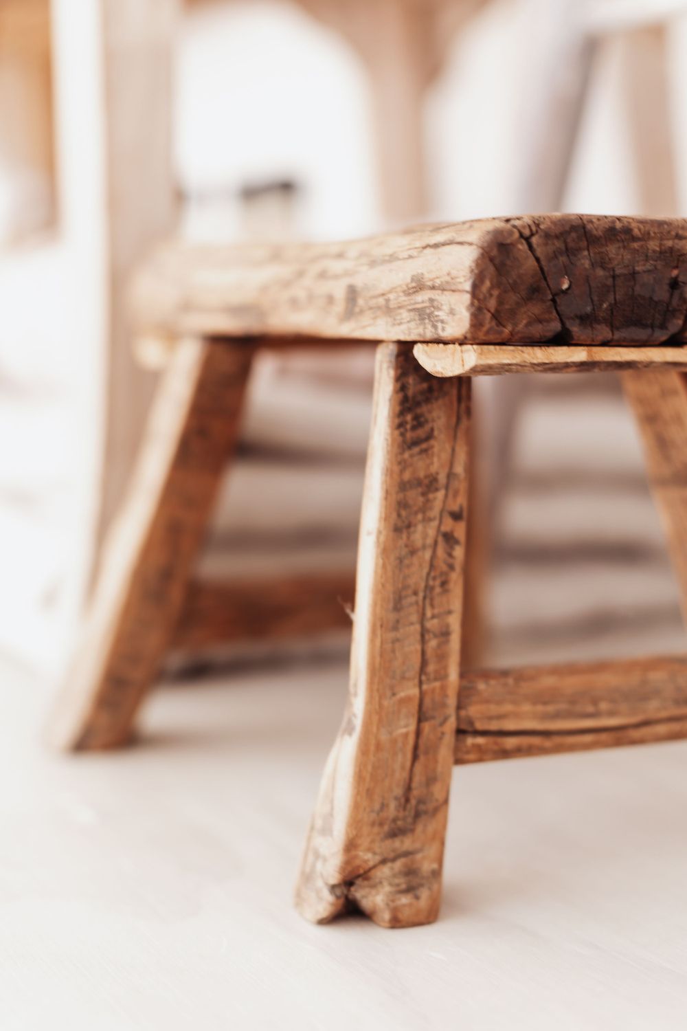 Vintage wooden stool detail showing rustic texture and weathered legs.