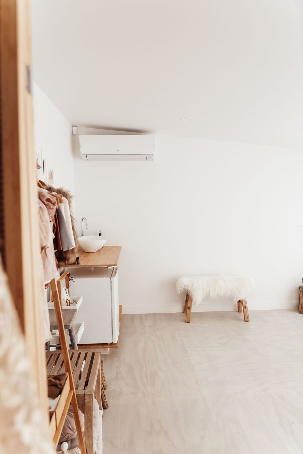 Minimalist room interior with wooden storage and white fur bench.