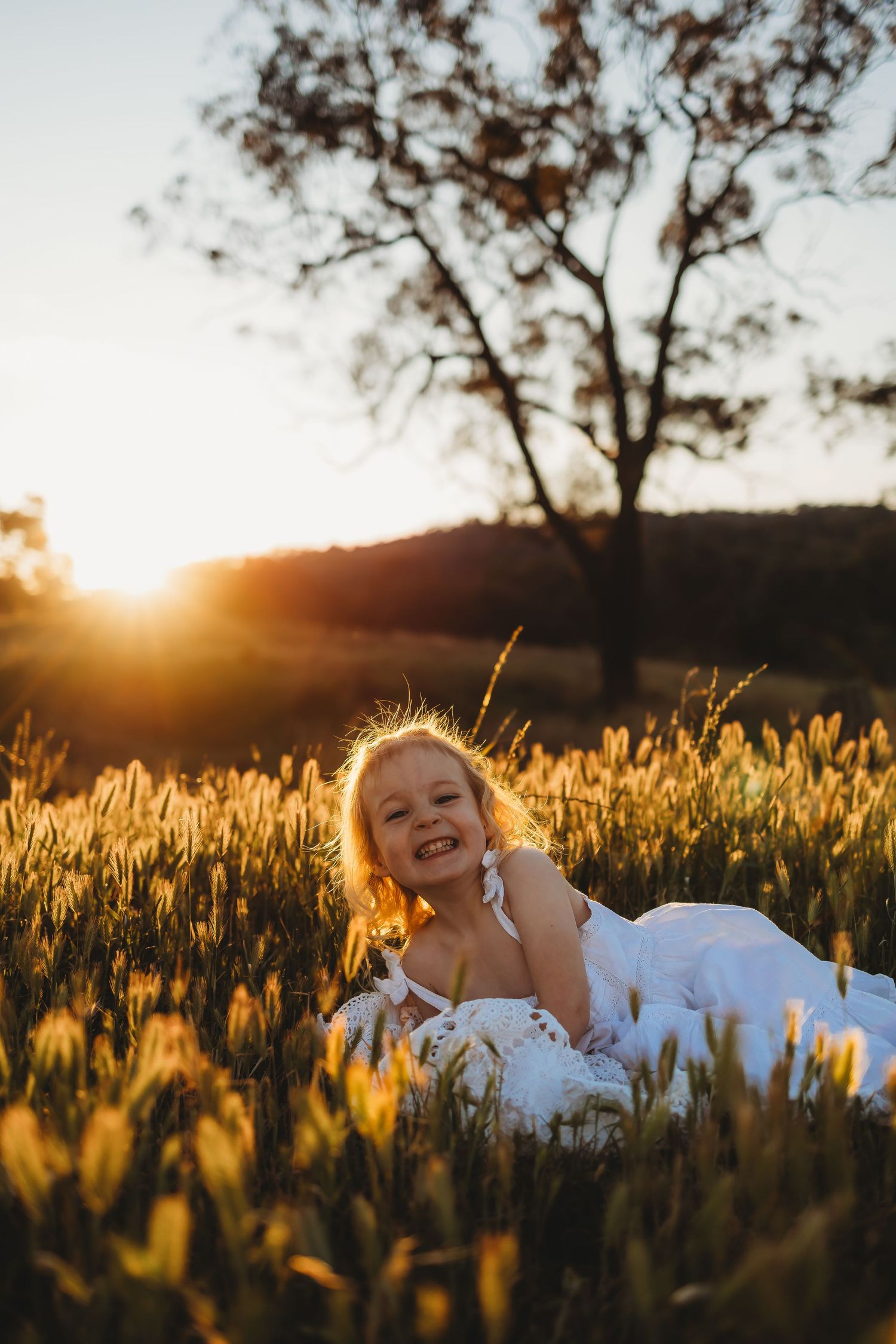 A joyful moment captured in a golden wheat field at sunset with warm backlighting creating a magical glow.
