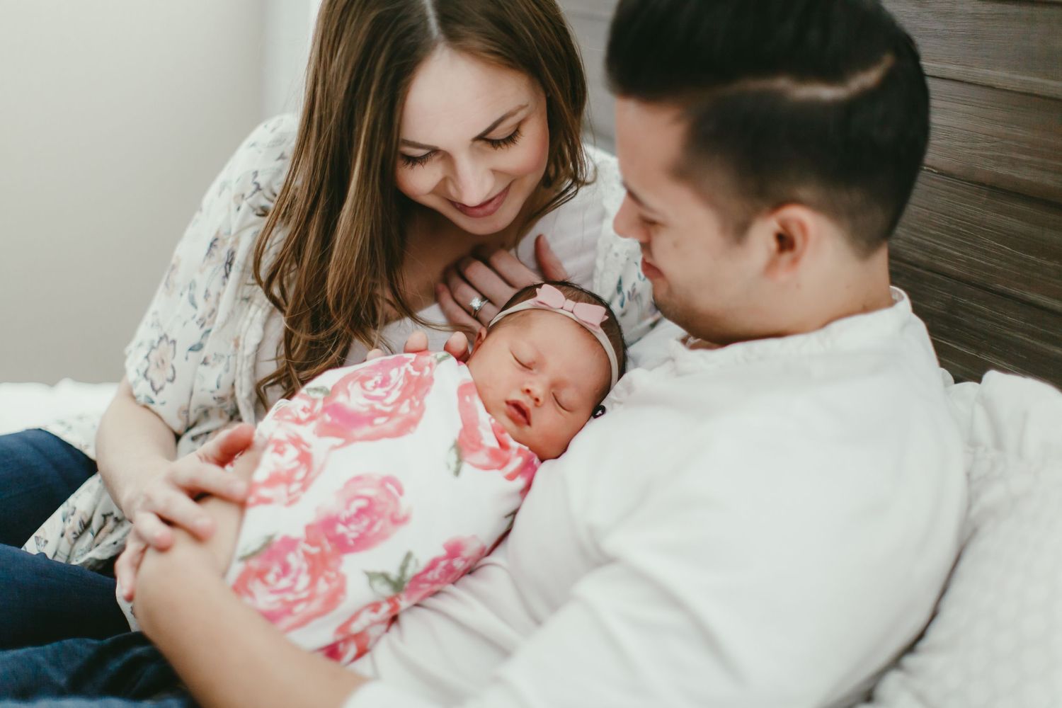 A tender moment with a newborn baby wrapped in a floral blanket on a cozy bed.