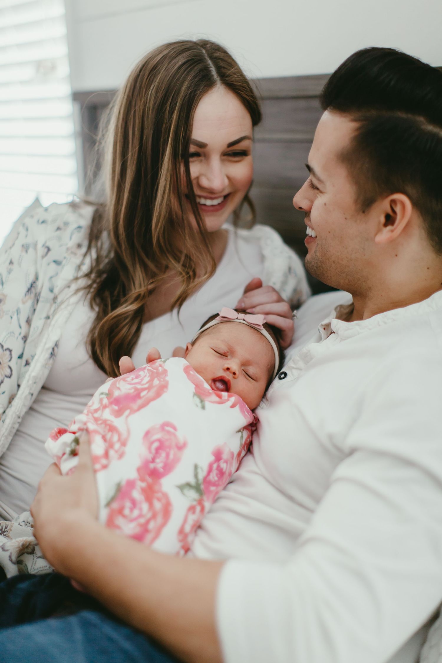 An intimate family moment with a newborn baby wrapped in a pink floral blanket.