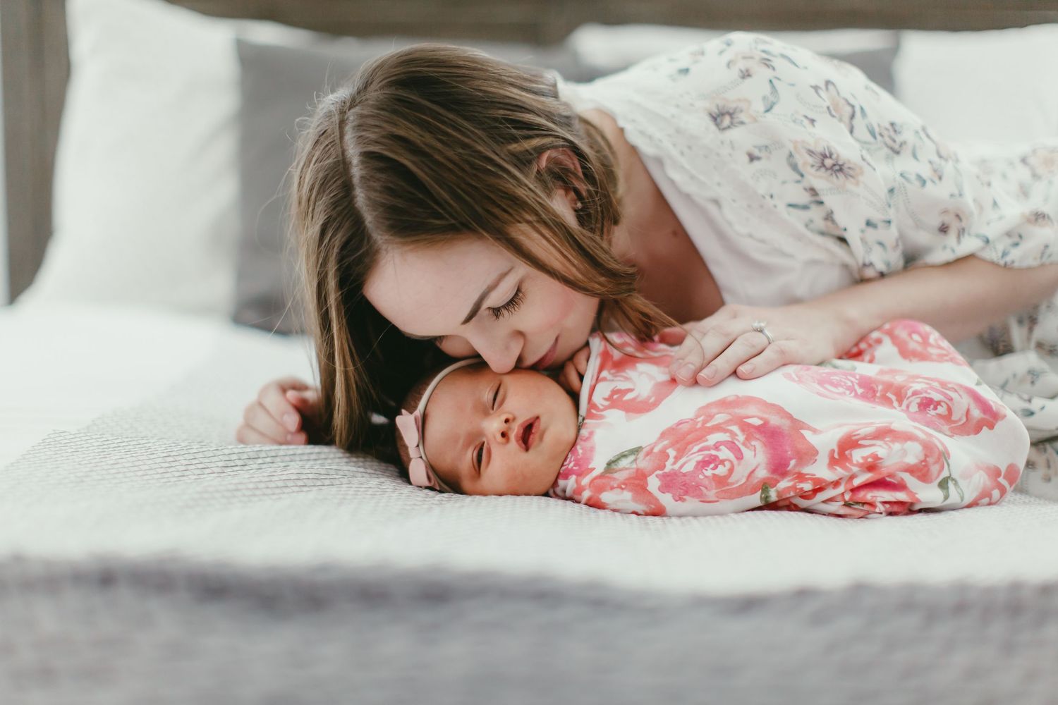 A tender moment between parent and baby on a gray bedspread.