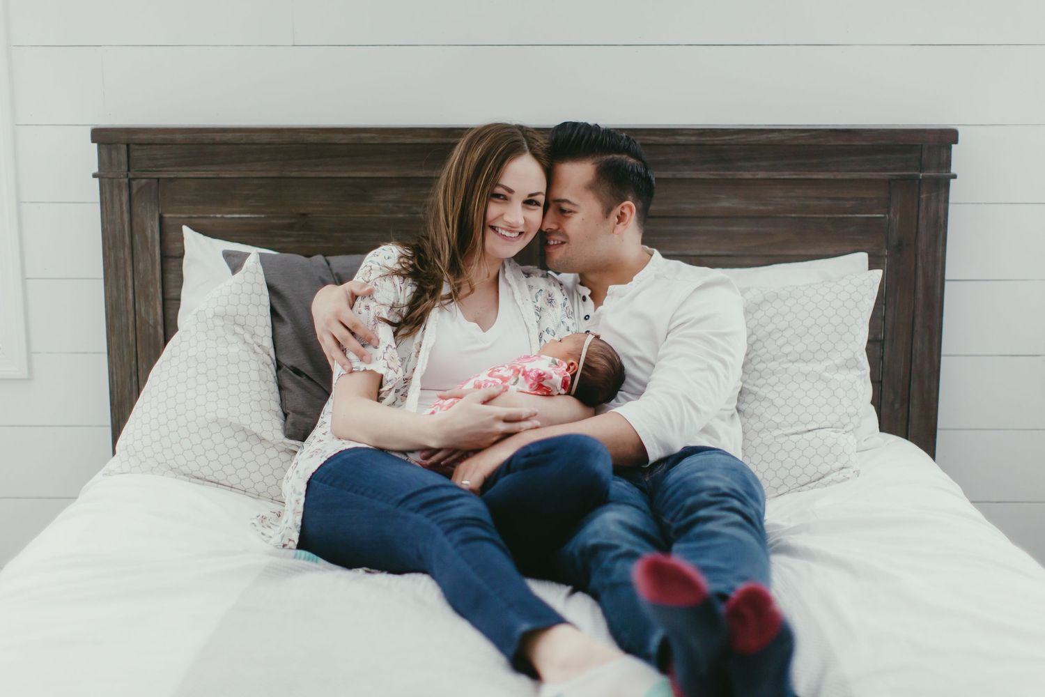 A family relaxing together on a bed with rustic wooden headboard.