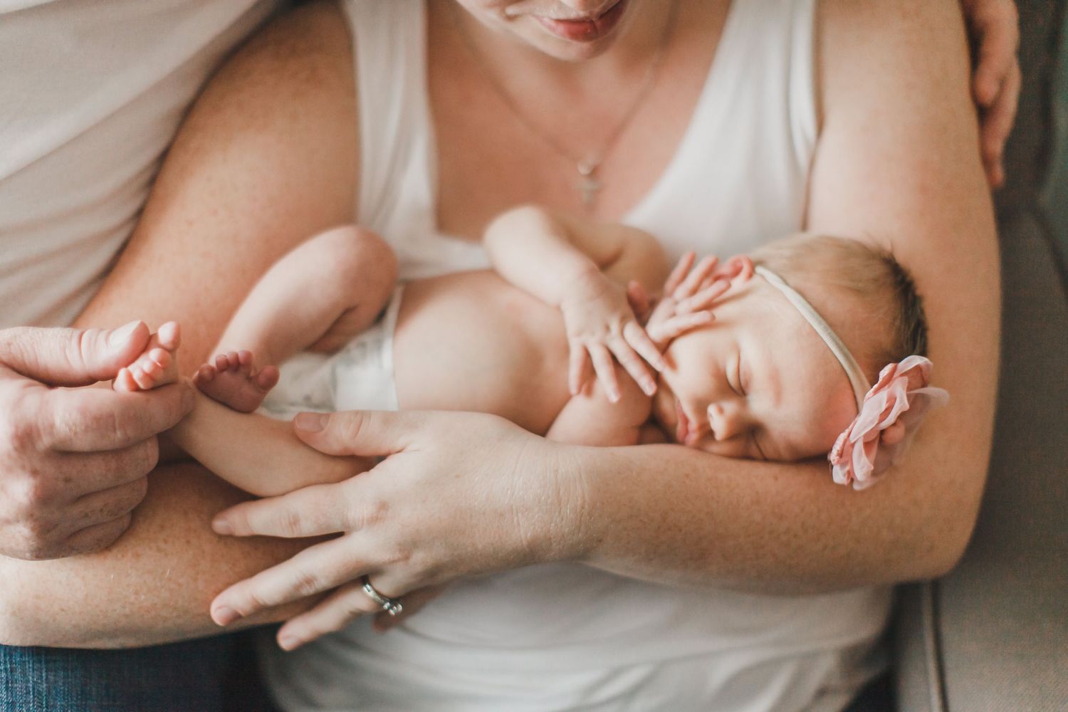 Tender moment of a baby resting in gentle embrace against white clothing.