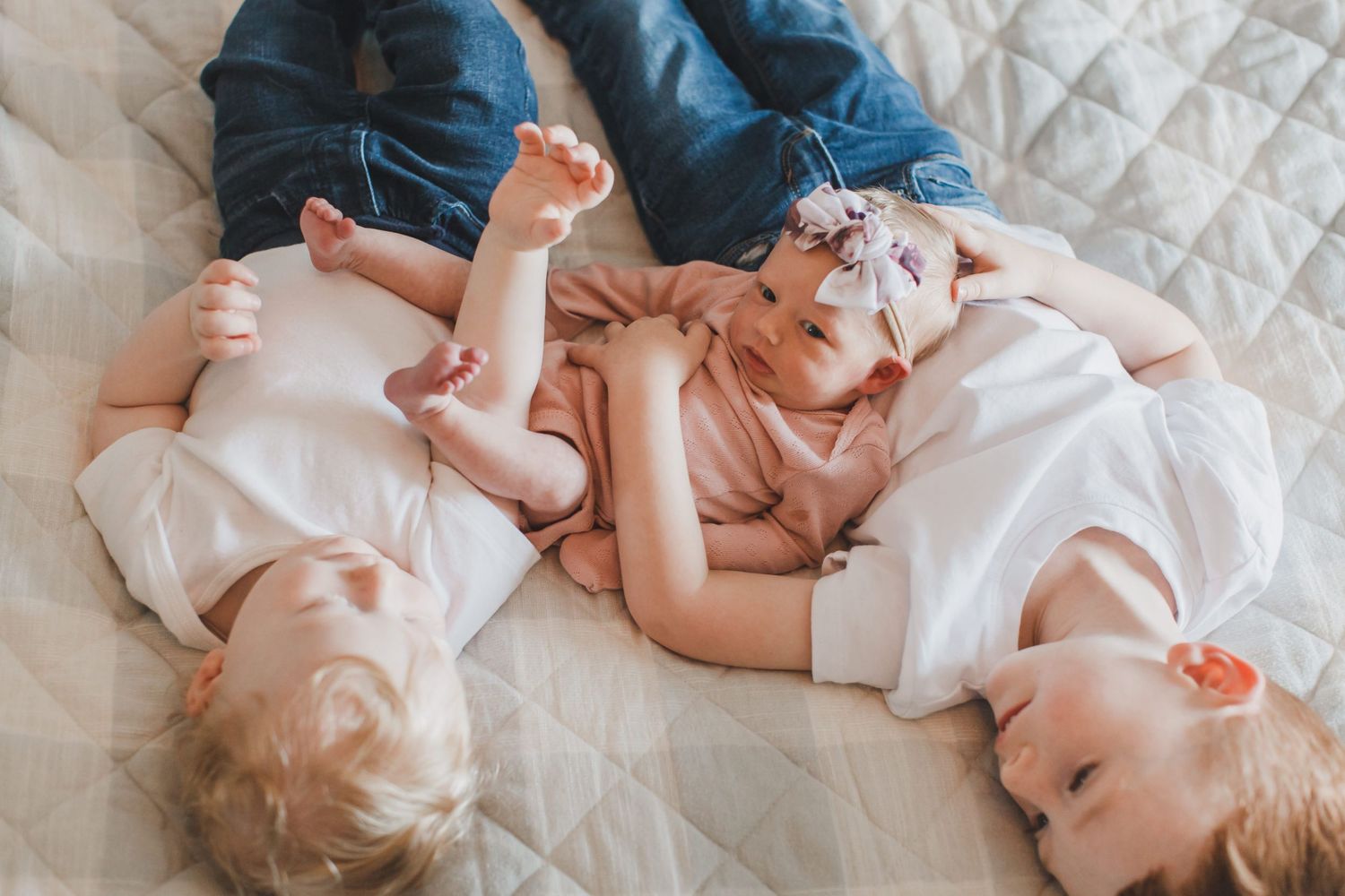 Playful family interaction on quilted white bedding during lifestyle photoshoot.