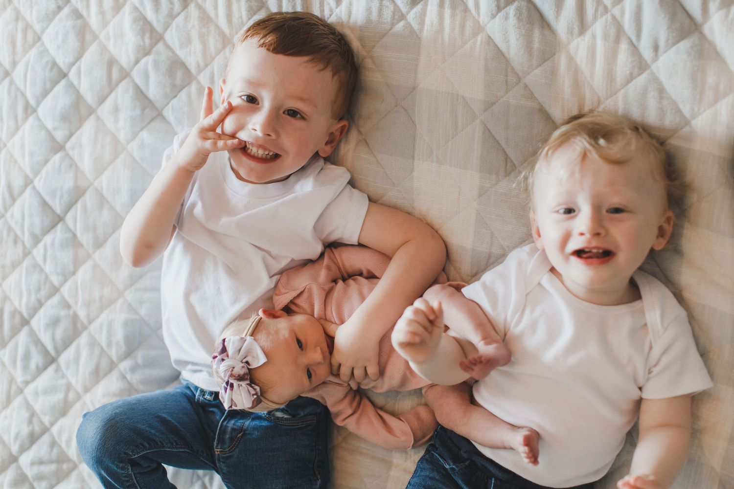 Natural lifestyle family photography session on white quilted bedding.