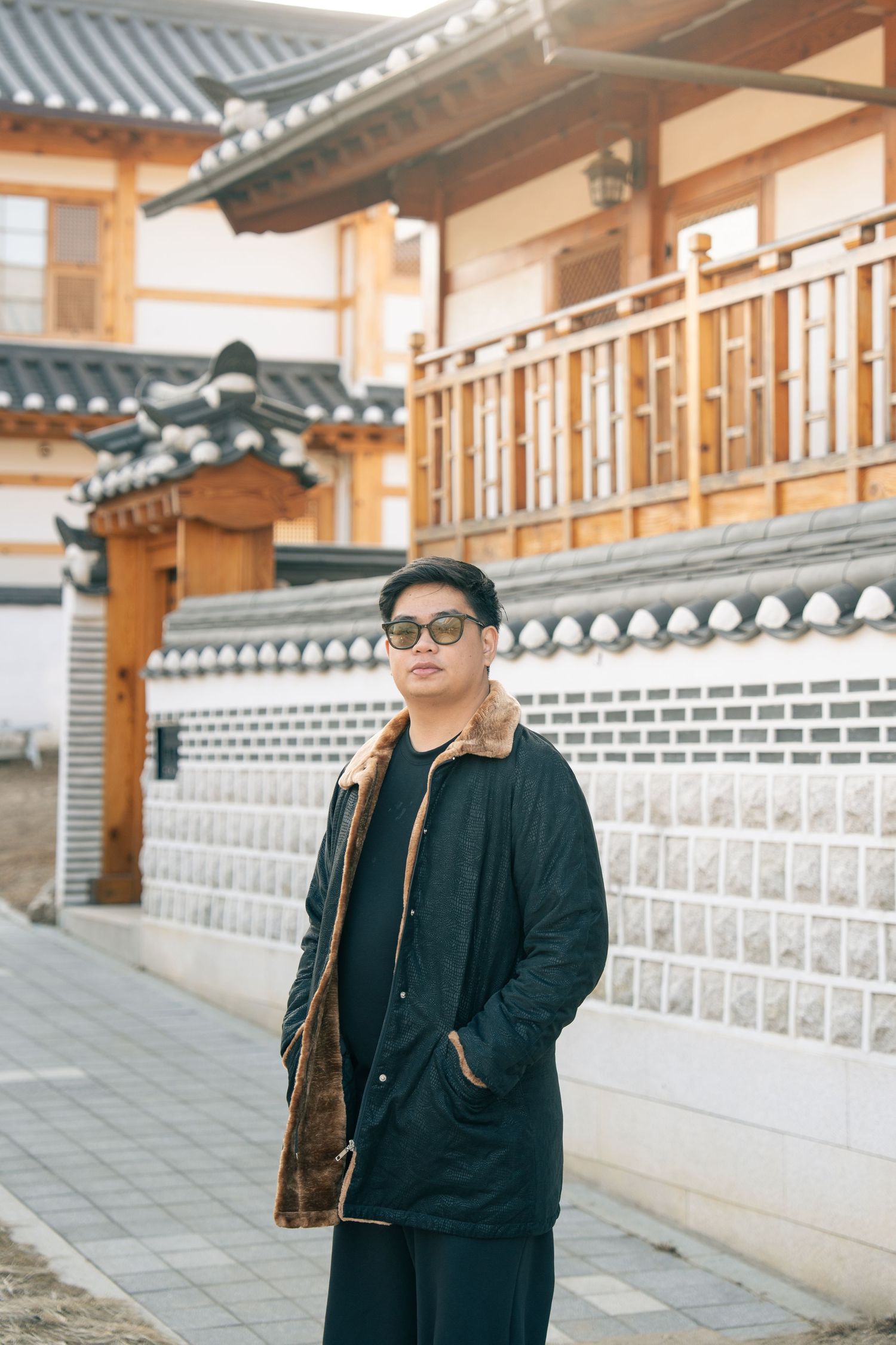 A series of four photos showing someone in a black jacket walking along traditional Korean palace walls with white stone patterns.