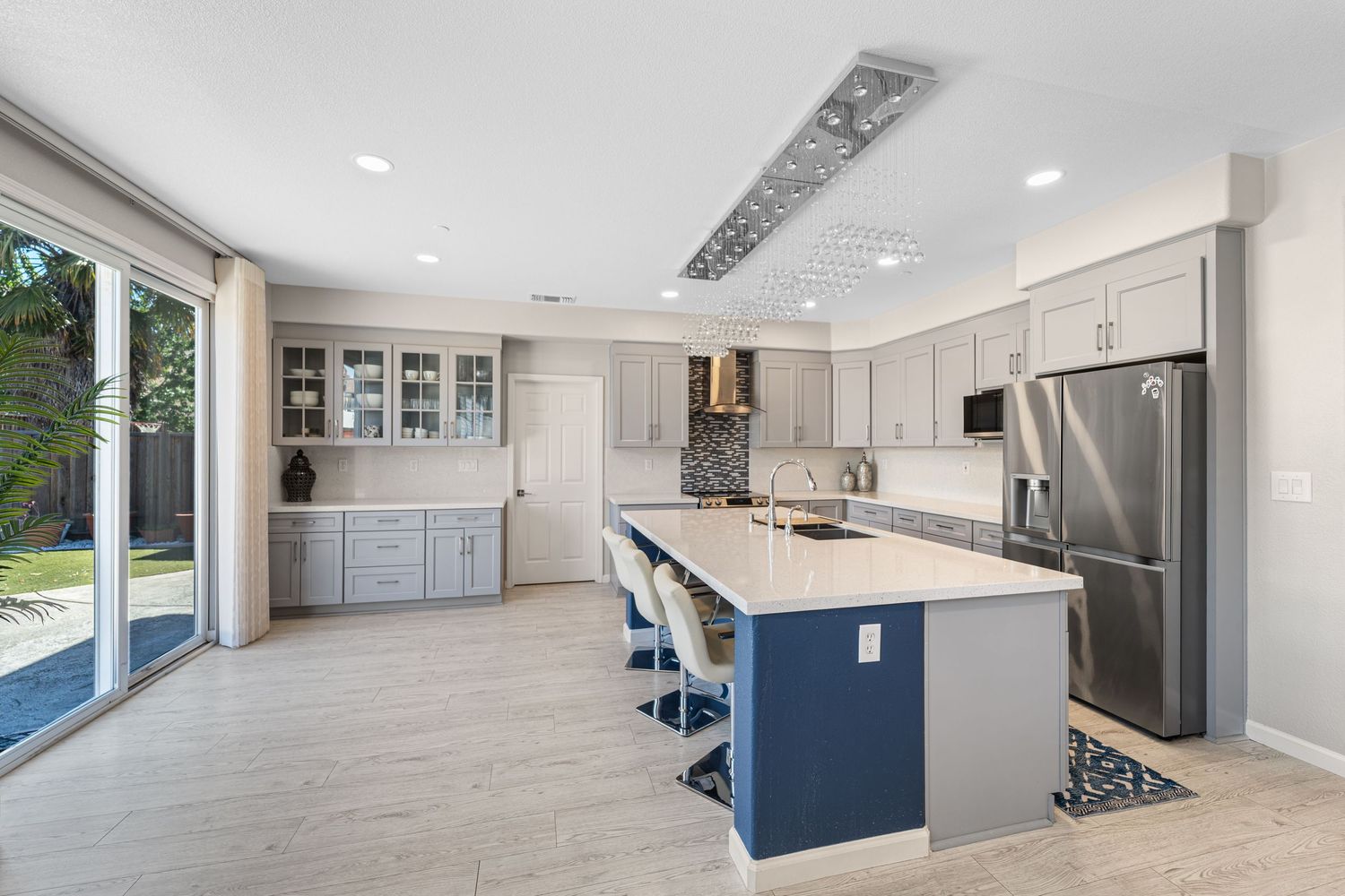 Modern white kitchen features sleek cabinetry, recessed lighting, and blue accent walls in an open-concept layout.
