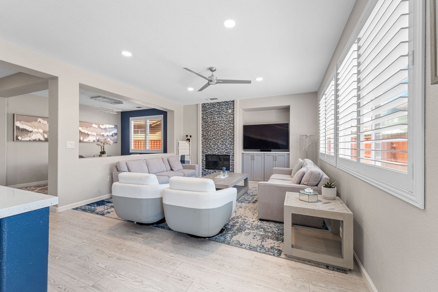 Contemporary living space with white plantation shutters, grey furniture, and built-in entertainment center.