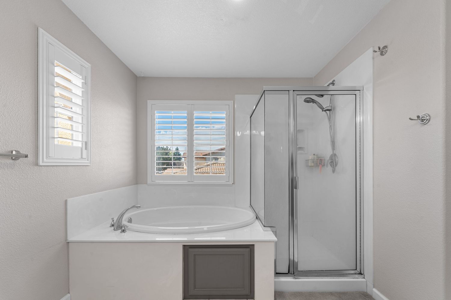 Clean white bathroom featuring glass shower enclosure, modern fixtures and natural lighting.